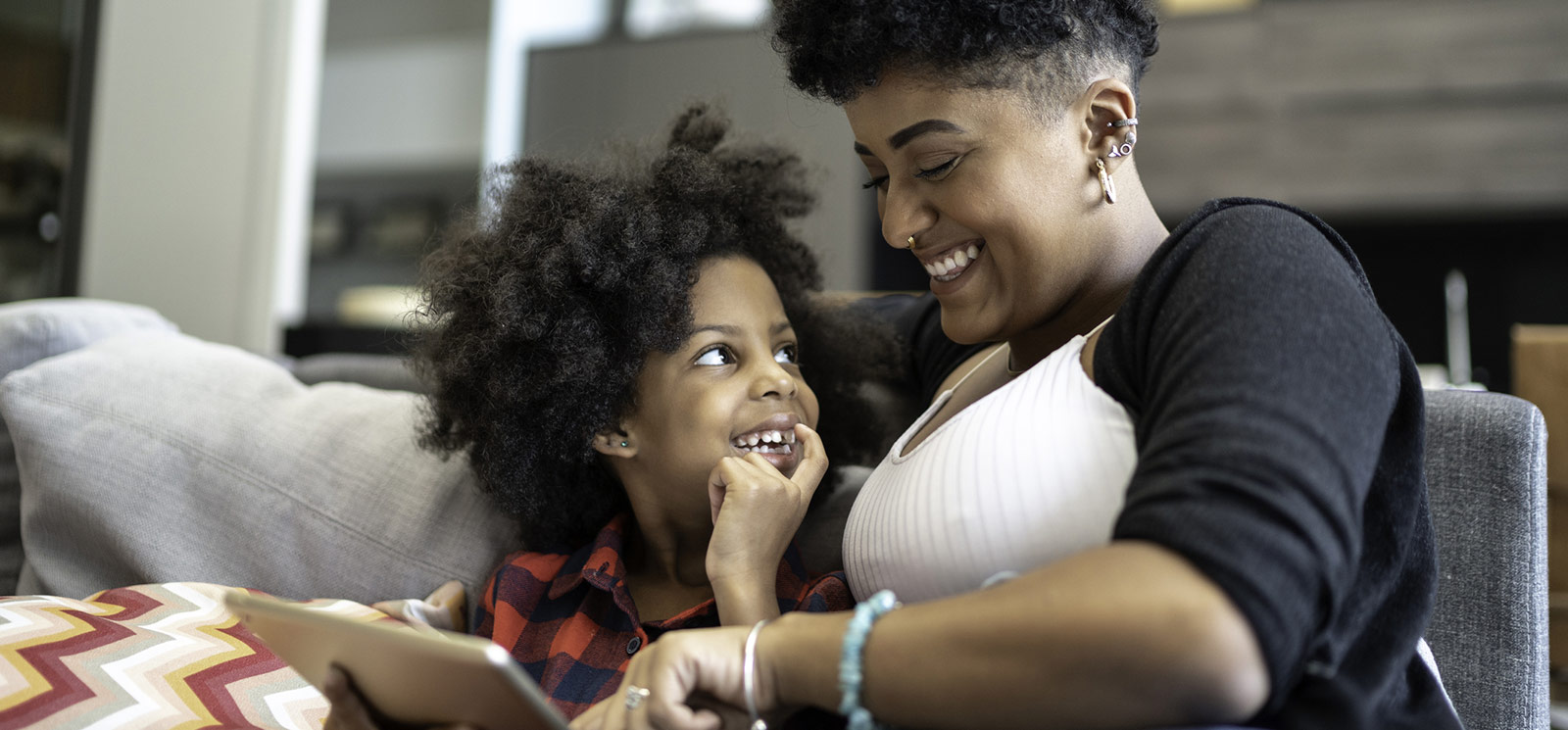 Mother and daughter looking at tablet in living room.