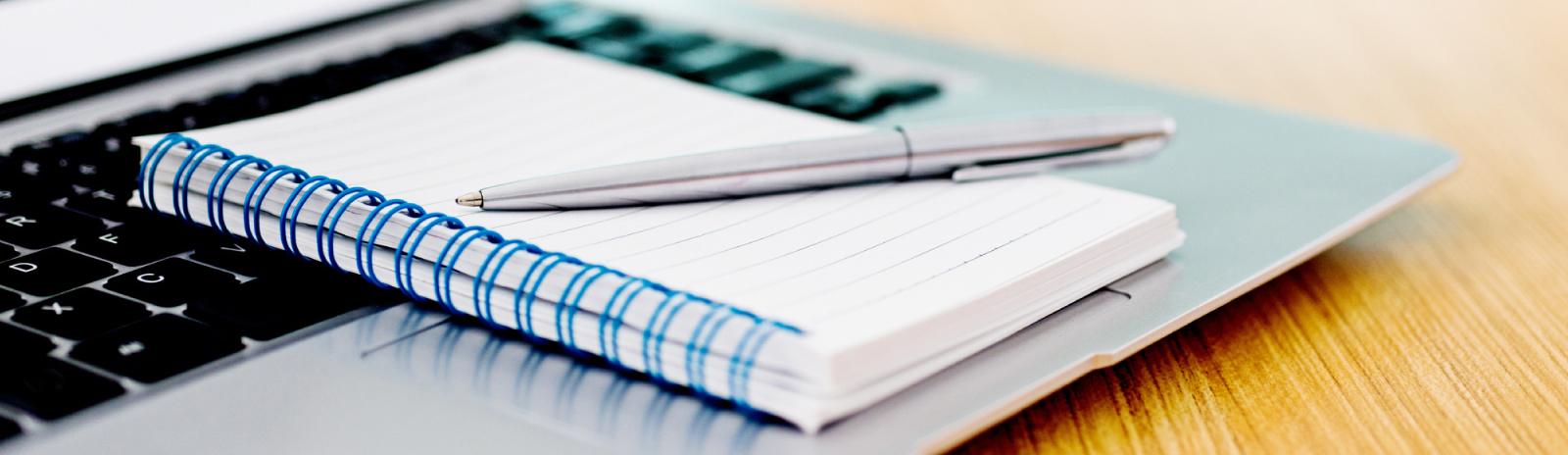 a pen on top of a notepad, on top of a laptop keyboard